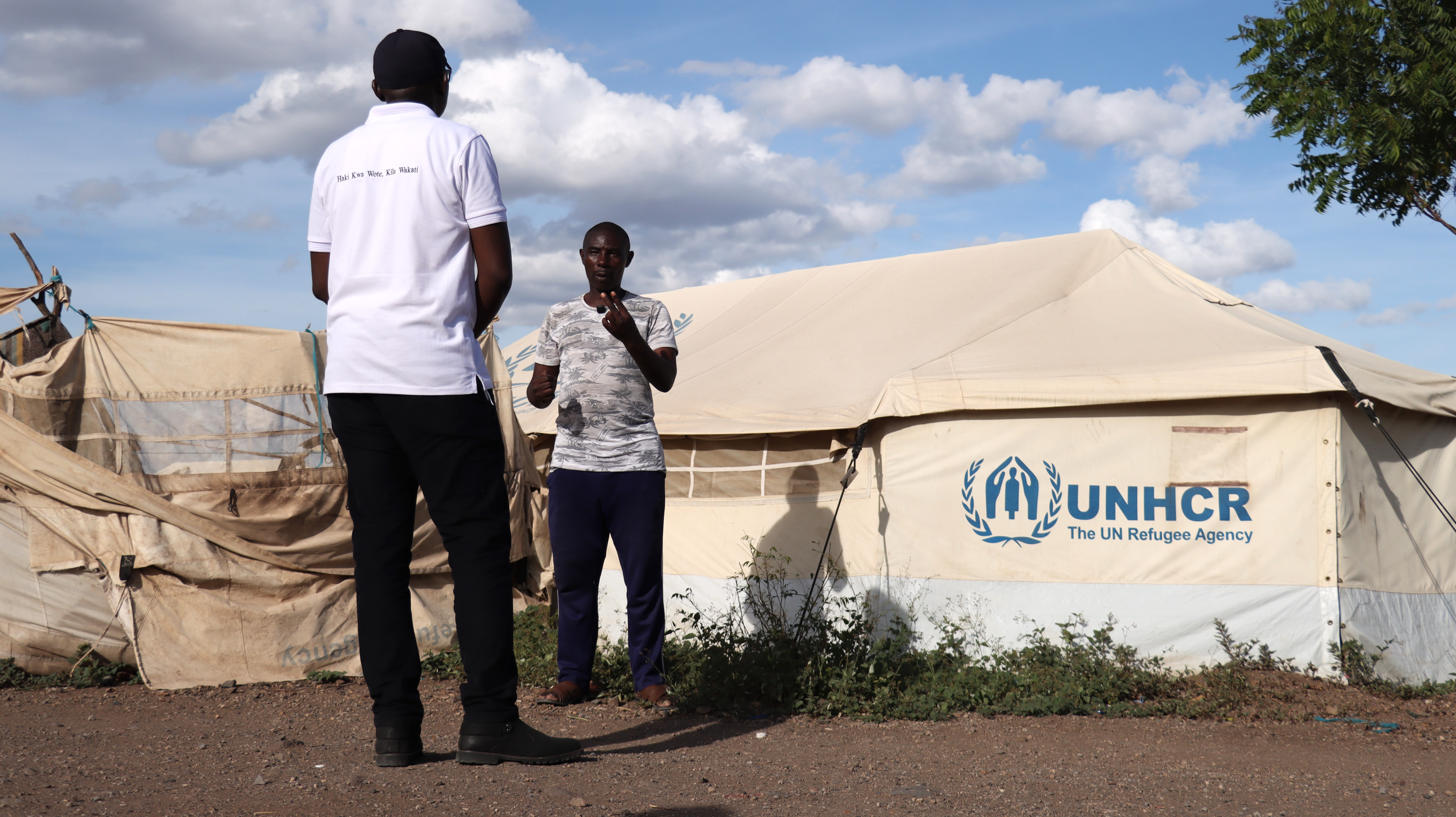 KNCHR's Mr. Daniel Mule (in white t-shirt ) interviewing an onward mover at the Kalobeyei Reception Centre